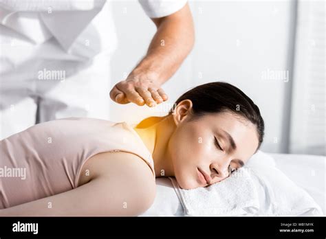 Cropped View Of Healer Standing Near Woman Lying With Closed Eyes And