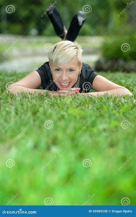 Attractive Blonde Girl Posing In Nature Lying On Grass Stock Photo