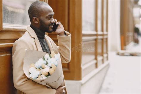 African Man With Bouquet Of Flowers Waiting For Girlfriend Stock Photo