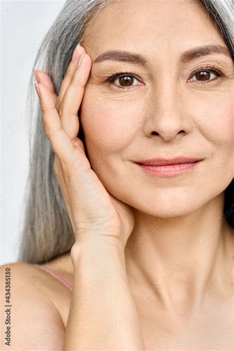 vertical portrait of middle aged asian woman s face with perfect skin older mature lady