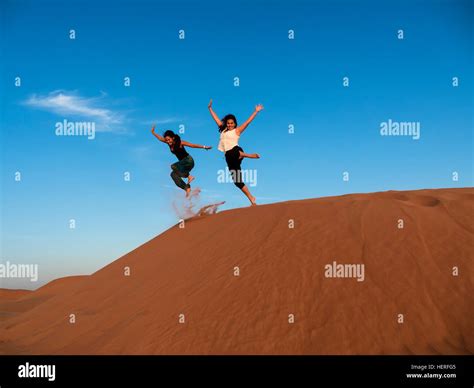 Two Young Women Jumping From Dune In Hi Res Stock Photography And