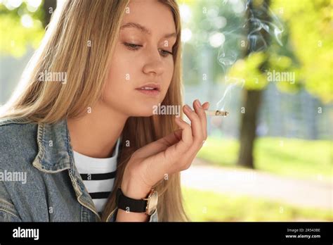 Young Woman Smoking Cigarette Outdoors On Sunny Day Stock Photo Alamy