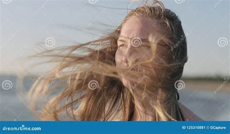 Closeup Portrait Of Young Girl Standing On A Beach And Wind Blows Her