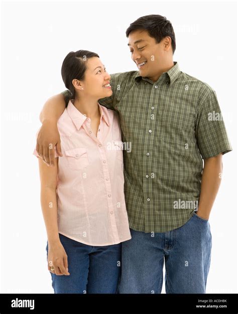 Mid Adult Asian Couple Standing With Arms Around Eachother And Smiling At One Another Stock
