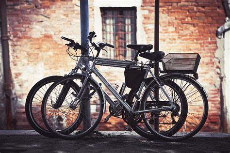 Two Bikes Resting Against Some Poles Photograph By Greg Stechishin
