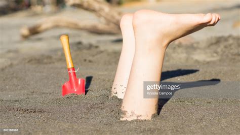 Girl Buried Upside Down In Sand At Beach High Res Stock