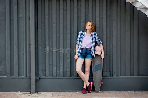 A Pretty Blond Girl Wearing Checkered Shirt And Denim Shorts Is