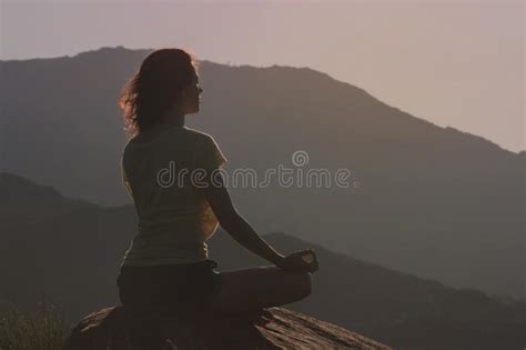 Woman Sitting On The Rock And Meditating In Yoga Pose Back View Stock