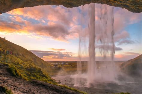 Seljalandsfoss Waterfall In Iceland Surrounded By Cliffs And Green Slopes