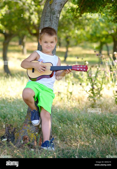 Cute Young Boy Playing Guitar Near The Summer Tree Stock Photo Alamy