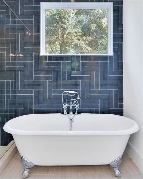 A White Bath Tub Sitting Under A Window Next To A Shower Head In A Bathroom