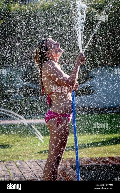 A Girl In A Pink Bikini Sprays Water From A Hose Stock Photo Alamy