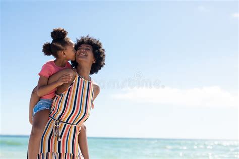 African American Girl Kissing Mother While Enjoying Piggyback Ride On