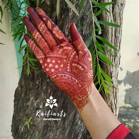 A Woman S Hand With Henna On It And Green Leaves In The Background