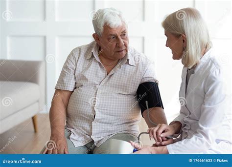 Mature Doctor Cardiologist Checking Older Man Blood Pressure During