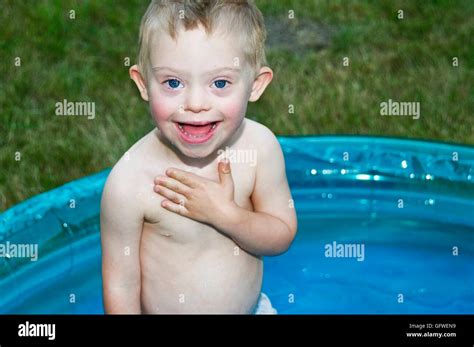A Young Boy With Downs Syndrome Playing In A Kiddie Pool And Making A