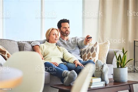 Couple Relax And Watching Tv On Sofa In Home Living Room Bonding And