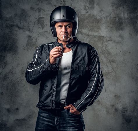 A Man In Motorcycle Helmet And Leather Jacket Smoking A Cigarette Stock
