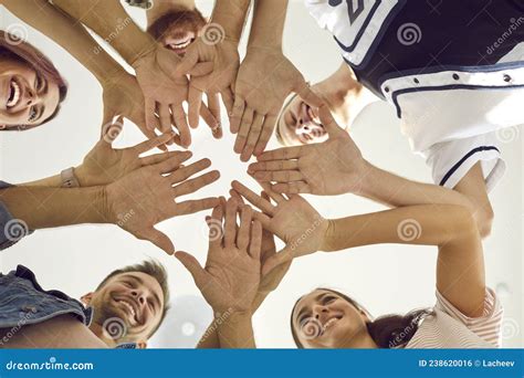 View From Below Of Group Of Happy Smiling Young People Putting Their