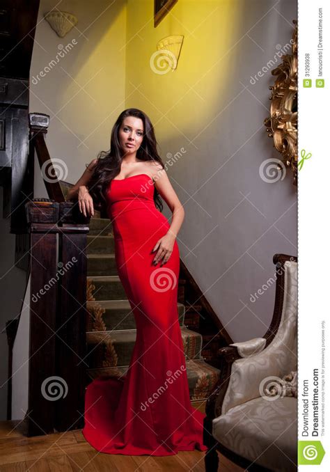 The Beautiful Girl In A Long Red Dress Posing In A Vintage