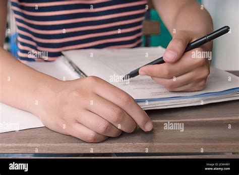 Person Writing A Document With Hand In Foreground On Blurry Background