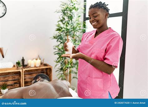 Young Physiotherapist Woman Smiling Happy Holding Oil Massage At The