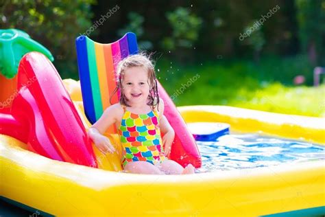 Маленькая девочка играет в надувной бассейн сад стоковое фото