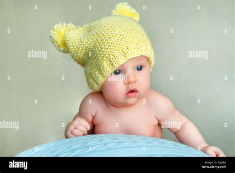Portrait Of A Cute Newborn Baby Girl In Yellow Knitted Hat Posing On