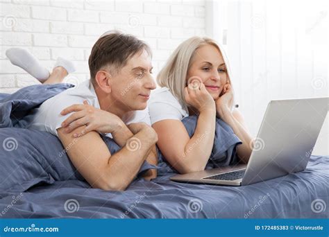 beautiful amorous couple using laptop on bed beautiful woman and handsome man read the news on