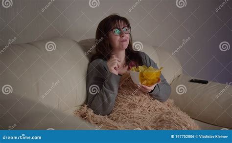 Happy Pretty Woman With Glasses Watching Tv In The Evening Eating Chips