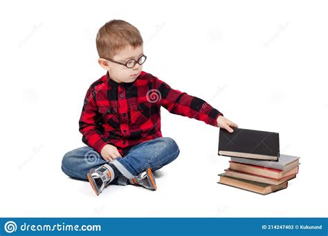 A Little Boy With Glasses Picks Up A Book From A Stack Of Books