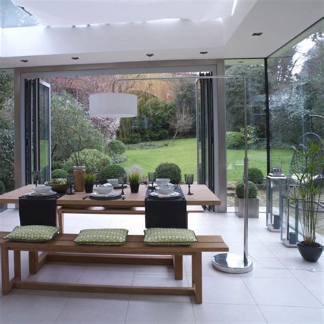 The crisp white living room is anchored by a sofa from jayson home and a papilio chair, creating an oasis of simplicity, ease, and eclecticism. 5 country rooms with beautiful bi-folding doors | Ideal Home