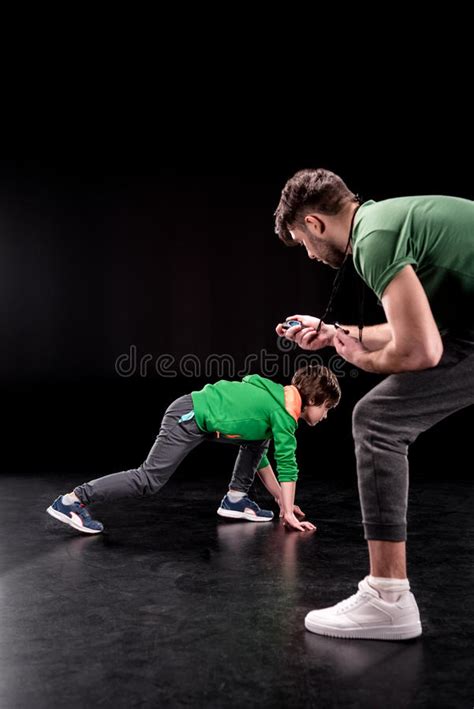Man Controlling Time While Boy Training And Looking To Camera Stock