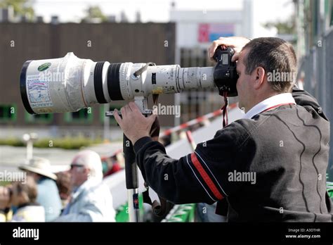 SPORTS PHOTOGRAPHER WITH A LONG CANON TELEPHOTO LENS PHOTOGRAPHING A