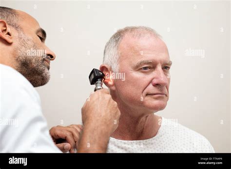 Doctor Using Otoscope While Examining Patients Ear In Hospital Stock