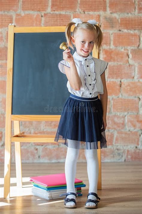 Cute Little Girl In School Uniform Posing Next To School Board With A