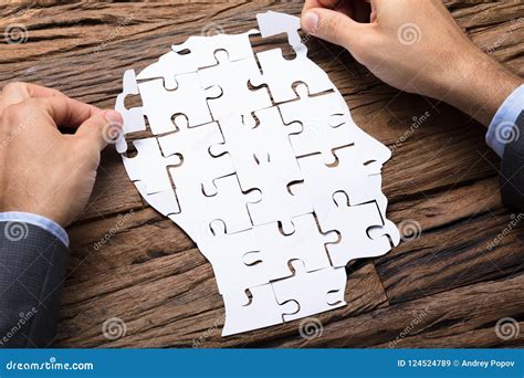 Businessman Making Head From Paper Jigsaw Puzzle Pieces On Table Stock
