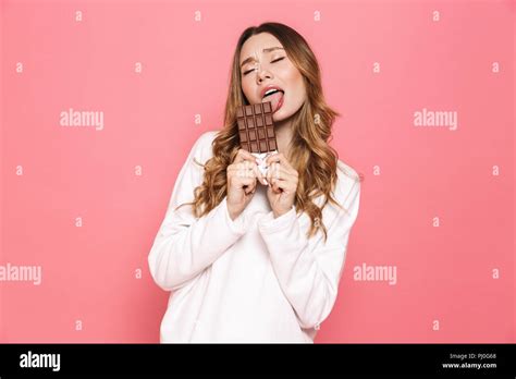 Portrait Of A Happy Young Woman Licking Chocolate Bar Isolated Over