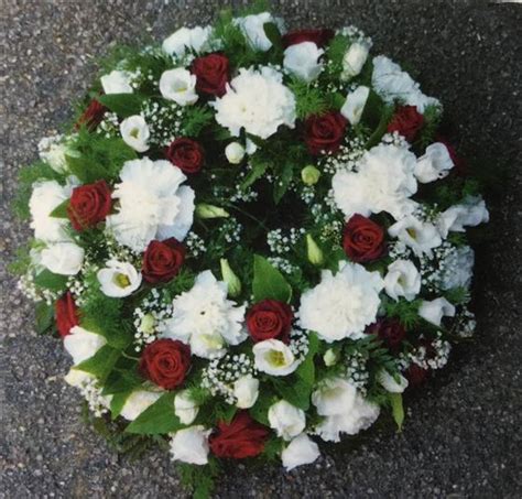 This style of funeral flower comes in the shape of an attractive arrangement and one that is suited both to the service and the home. Funeral Flowers - Red Rose and White Wreath