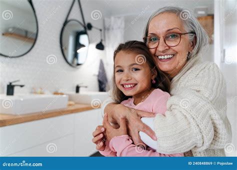 Senior Grandmother And Granddaughter Standing Indoors In Bathroom