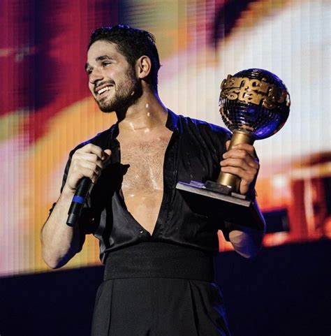 A Shirtless Man Holding An Award On Stage