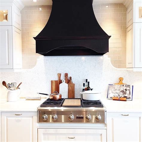 Range hoods are becoming more than just another appliance in the kitchen. white kitchen + black range hood | Kitchen range hood, Black kitchens, White kitchen range