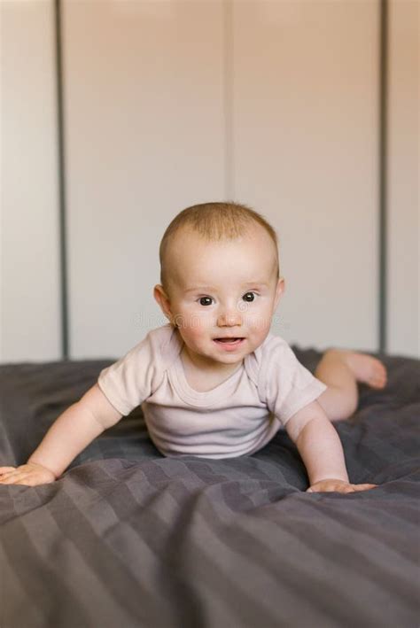 Cute Smiling Baby Boy In Bed Lying On His Belly In Bedroom Stock Image