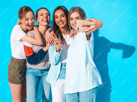 free photo girls taking selfie self portrait photos on smartphone models posing near blue wall