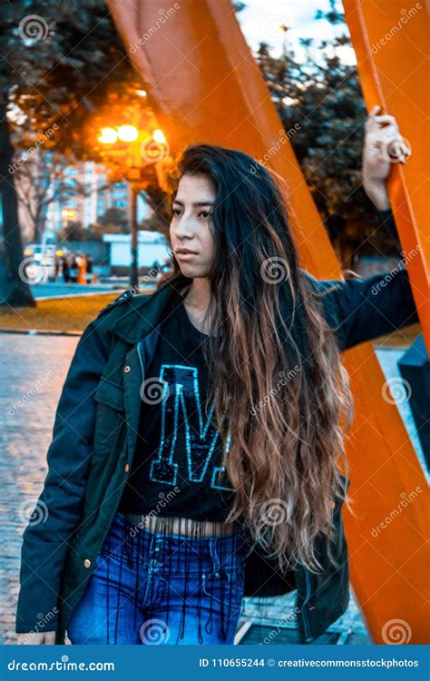 Woman Wearing Black Jacket Leaning On Orange Metal Picture Image