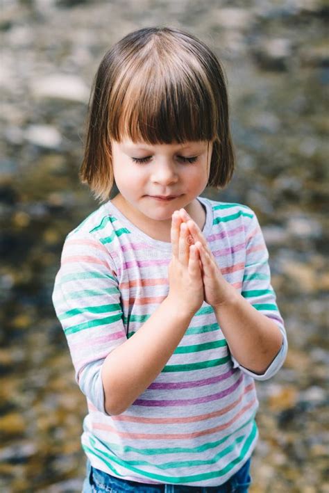 Little Girl Praying With Eyes Closed On The Shore Of A Stream Stock