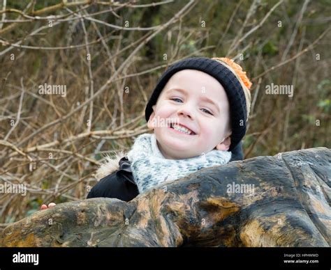 Portrait Of A Small Boy Playing Peek A Boo Outside In Winter Stock