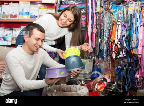 Happy Young Boyfriend Helping Girl To Choose Bowl In Pet Store Focus