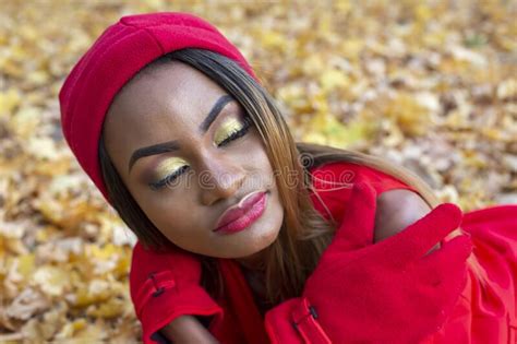 belle fille africaine dans les habits rouges assis sur des feuilles d automne photo stock