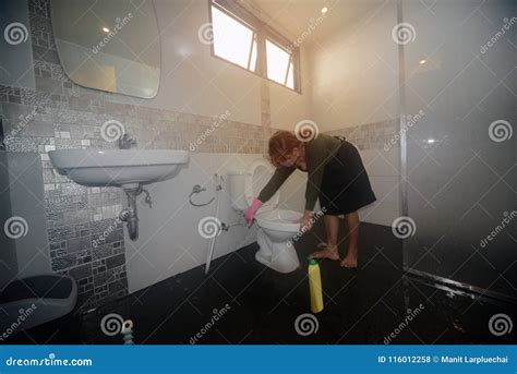 Asian Female Maid Or Housekeeper Cleaning On Lavatory In Toilet Stock